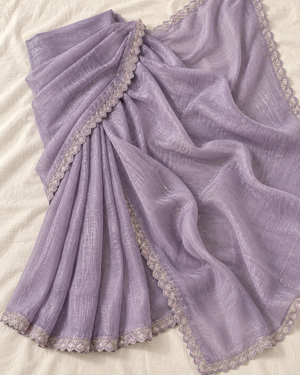 The lavender georgette saree laid flat on a cream cloth, showing its scalloped silver-toned border