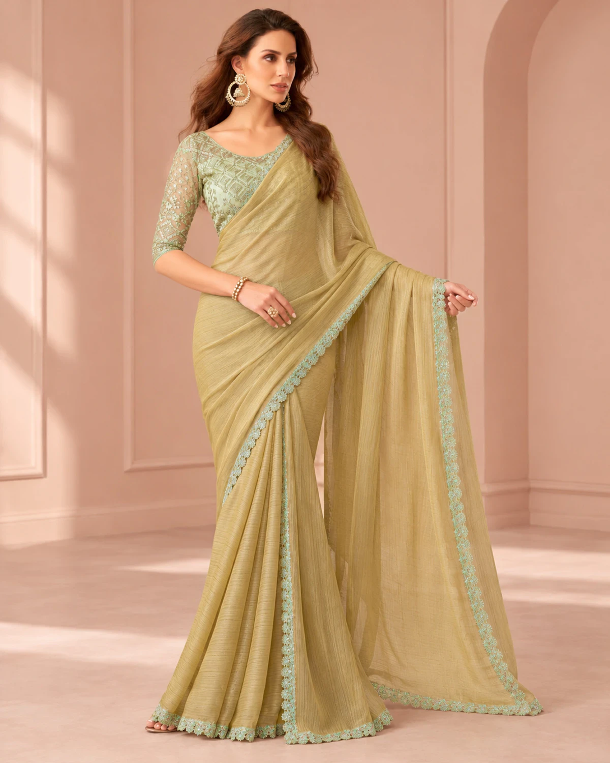 Woman holding out the pallu of the olive beige georgette saree in a softly lit room