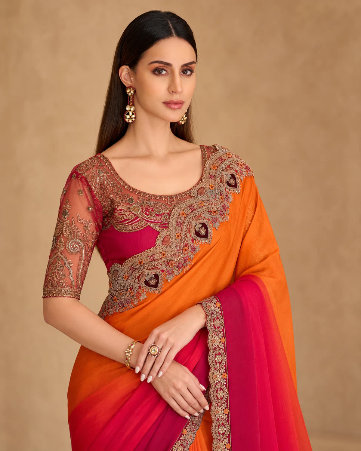 Close-up of the orange and red satin chiffon saree's embroidered shoulder and the pink-red embroidered blouse