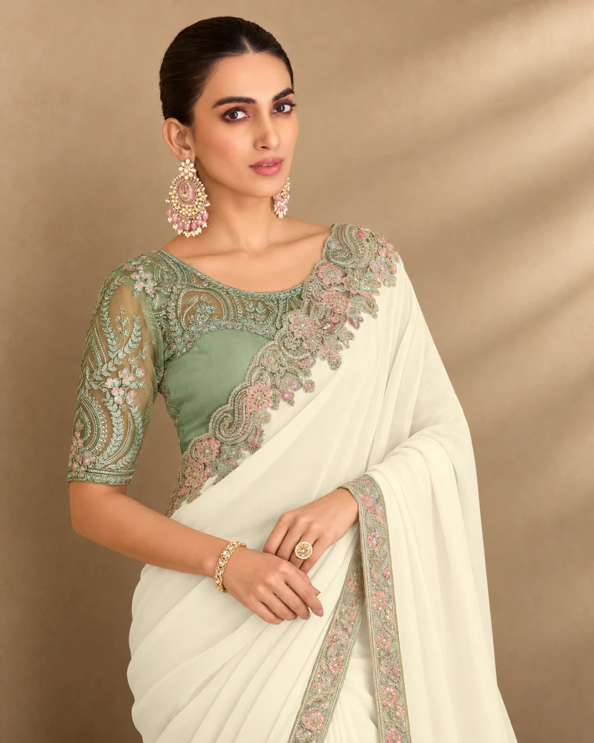 Close-up of the ivory satin saree's embroidered shoulder and the sage green embroidered blouse
