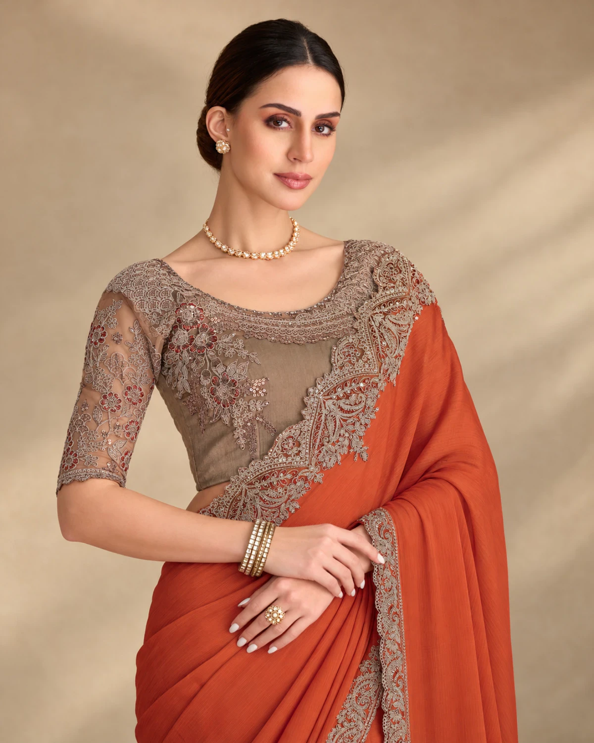 Close-up of the rust satin chiffon saree's embroidered shoulder and the taupe embroidered blouse