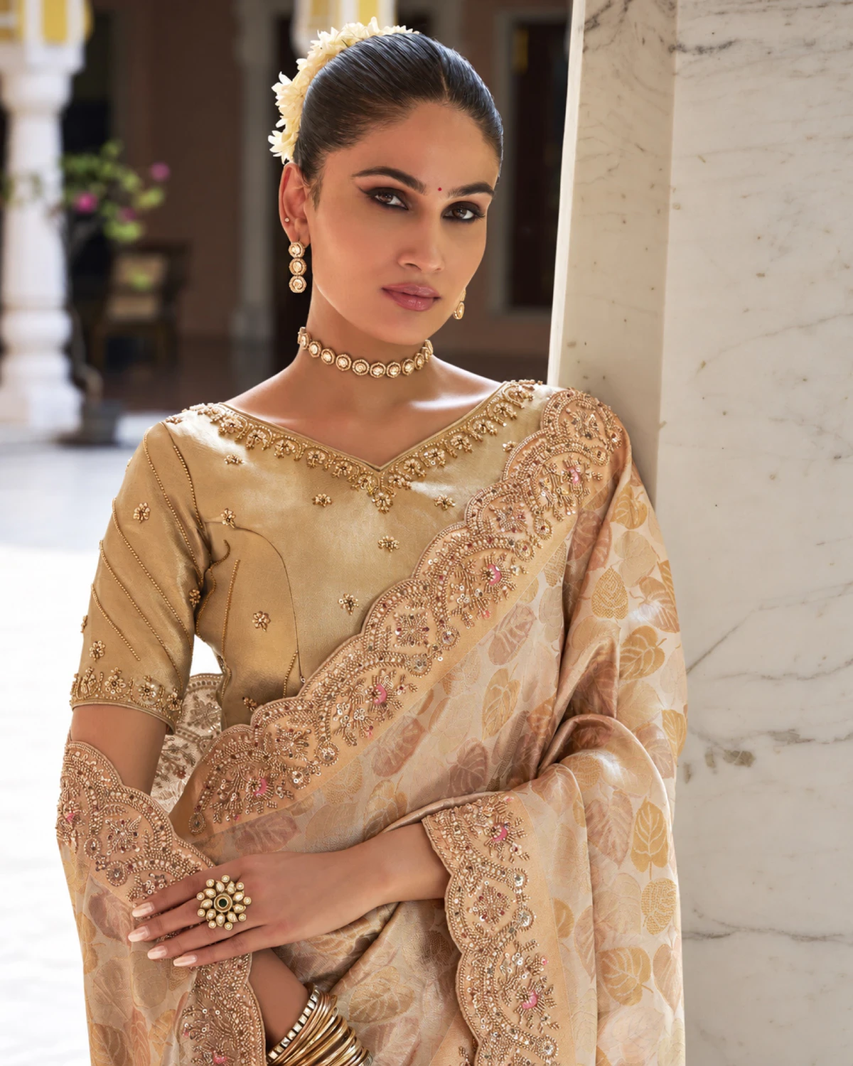 Close-up of the champagne gold saree's scalloped border of moti, beads and sequins and the beaded gold blouse