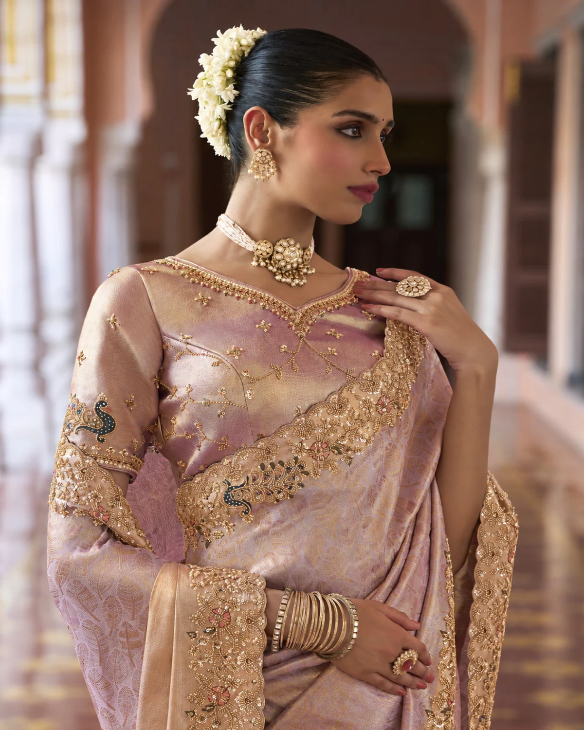 Close-up of the dusty lilac saree's peacock border and the peach-gold blouse with peacocks on the sleeves