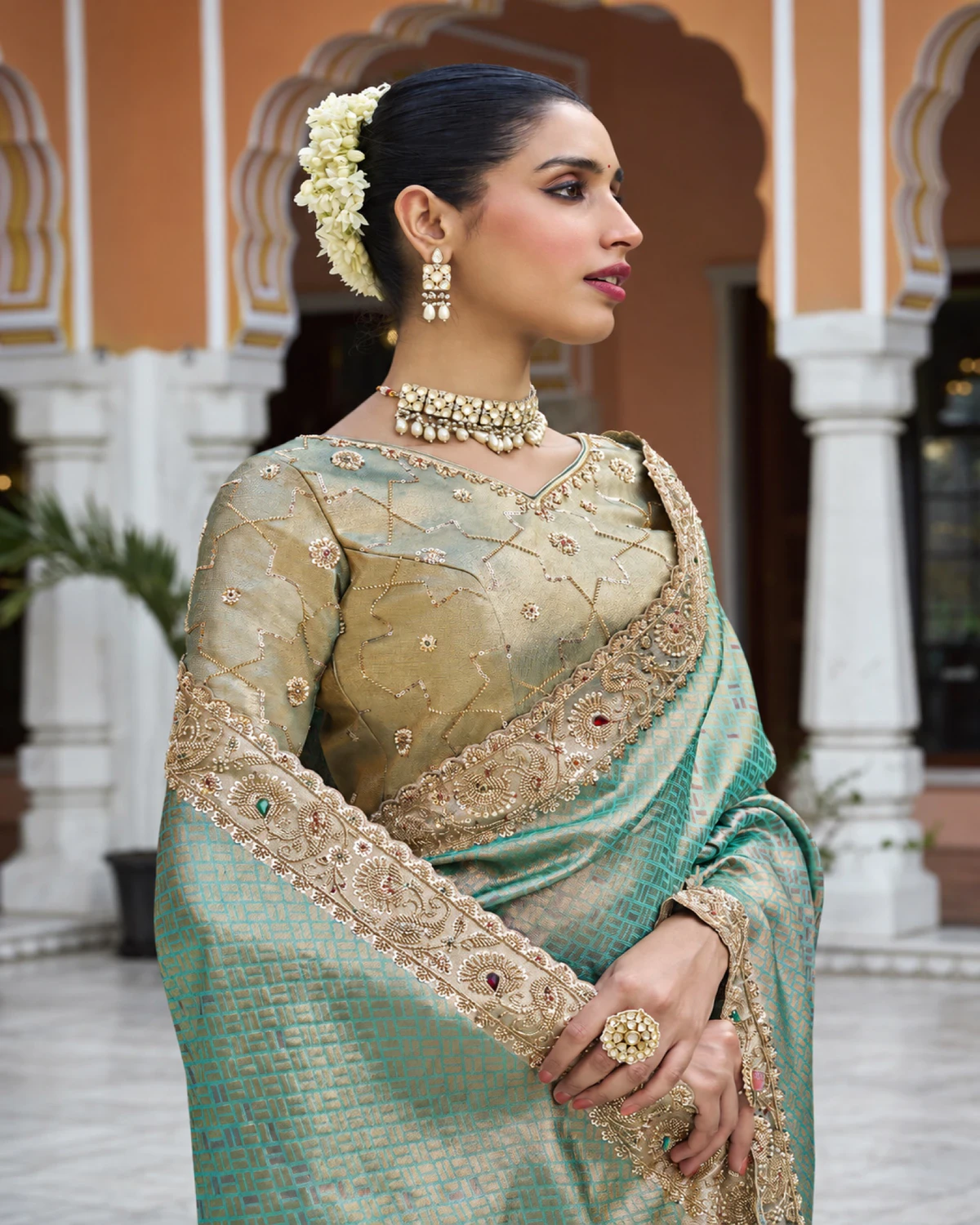 Close-up of a woman in a mint green Kanjivaram-style soft silk saree with a beaded border and a gold blouse