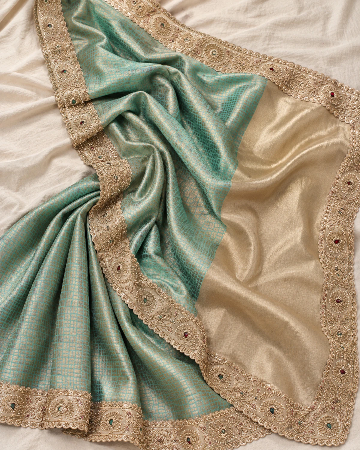 The mint green soft silk saree laid flat on a cream cloth, showing its gold grid, beaded border and gold pallu